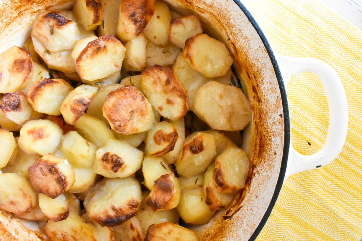 Close up of lamb hotpot in ovenproof dish, on yellow cloth.
