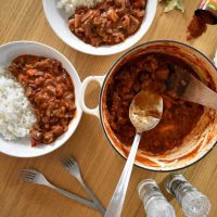 Cooking pot filled with leftover beef chilli, 2 portions in bowls at side