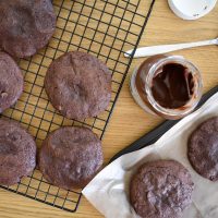 cookies on wire rack, open jar of nutella on table