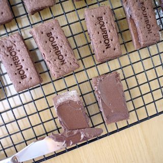 top view of biscuits on wire rack, one open and being spread with buttercream