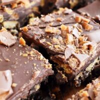 close up of square of chocolate tiffin topped with crushed daim bars