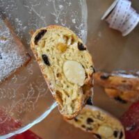 Close up of slice of stollen on glass cake stand, on side so you can see the marzipan and fruit