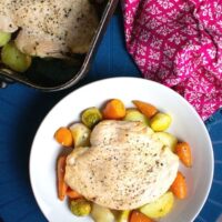 Served turkey steak and vegetables in bowl, roasting tin at the top of shot