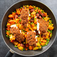 top view of breaded cod and hash in frying pan.