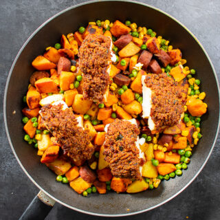 top view of breaded cod and hash in frying pan.
