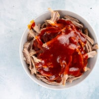 Bowl of pulled pork topped with BBQ sauce.
