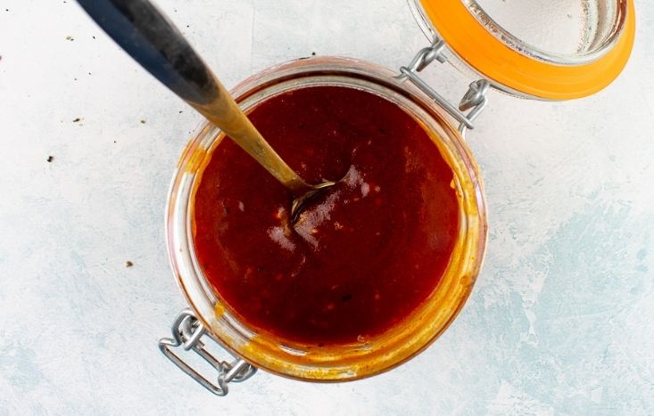 Top view of BBQ sauce in jar with spoon.