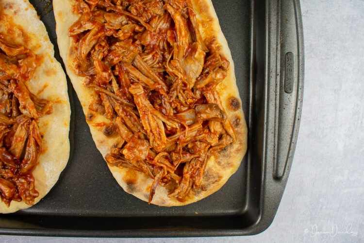 flatbread topped with bbq pulled pork on baking tray.