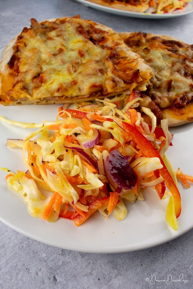 Cut in half pulled pork flatbread served on plate with crunchy coleslaw.