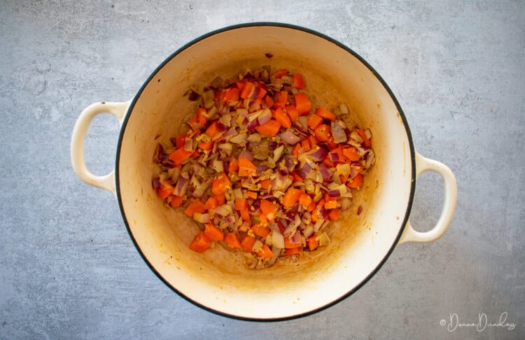 Carrots, onion and garlic in cast-iron cooking dish.