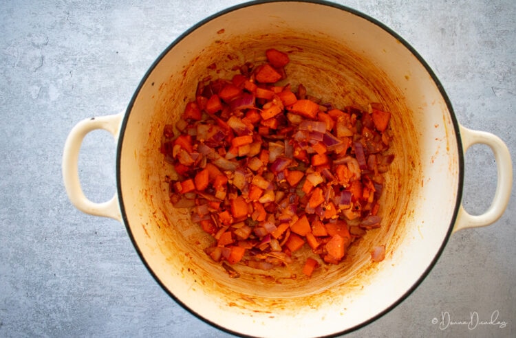 carrots, onion, garlic and tomato puree in cast-iron cooking dish.