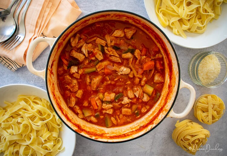Turkey Ragu on table, bowls of pasta and parmesan to the sides.