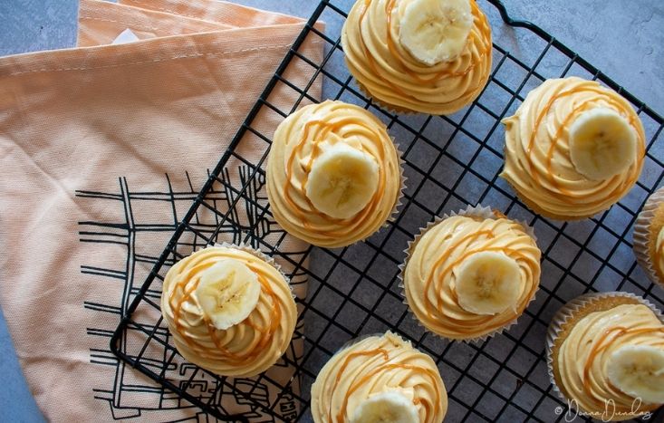 Banoffee Cupcakes topped with banana on wire rack.