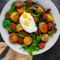 salad with broken poached egg, yolk running out.