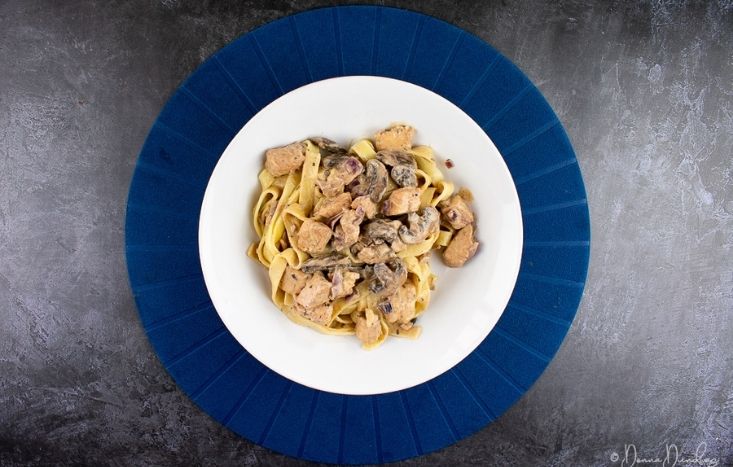 top view of served halloumi stroganoff in bowl, on blue placemat.