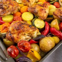lemon and herb chicken thighs and veg on baking tray.
