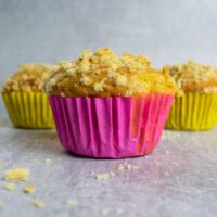 3 muffins in a row topped with crumble. crumbs on side.