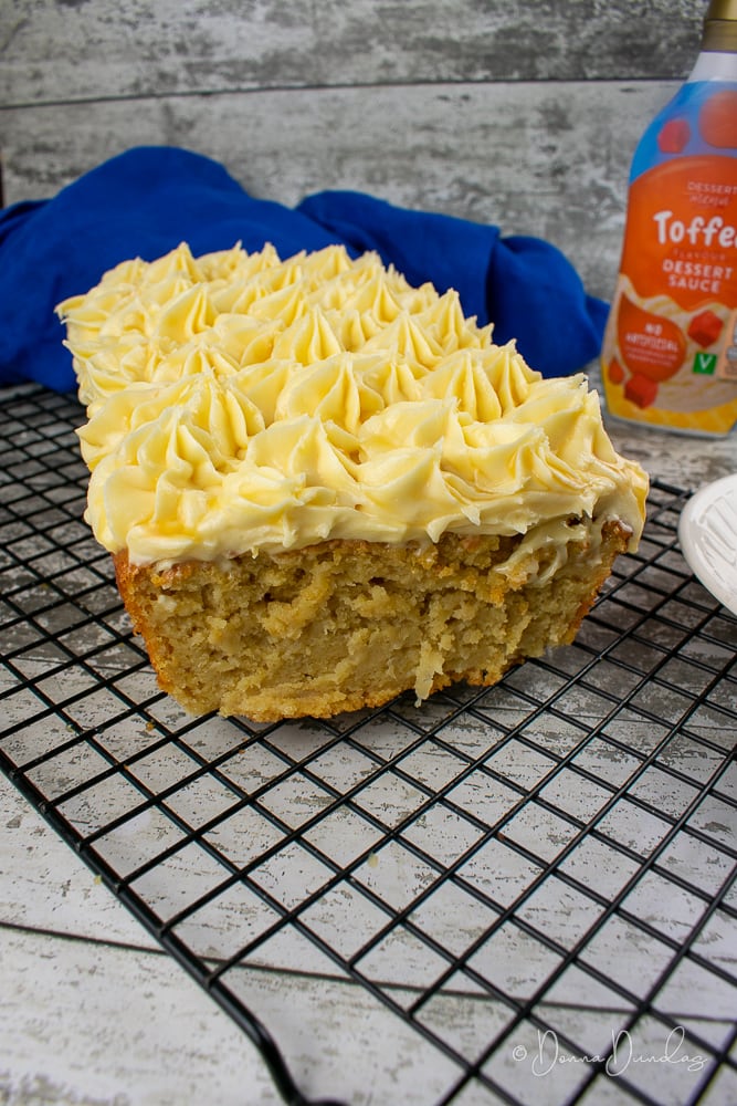 3/4 shot of cut cake on wire rack. Toffee sauce in the background.