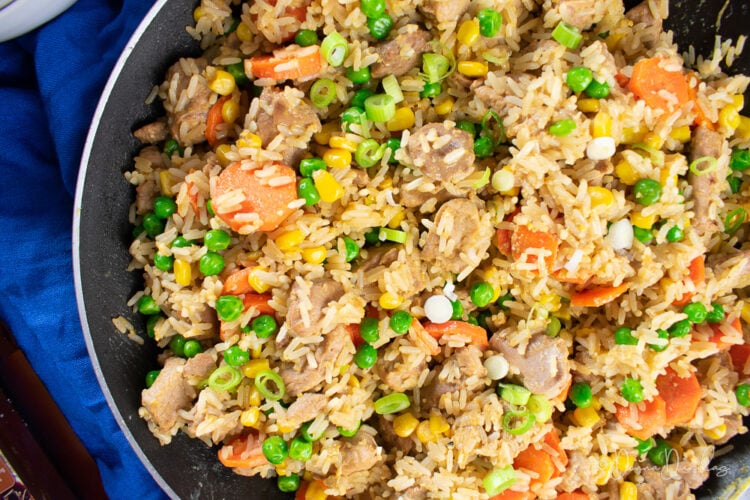 close up of fried rice with turkey thighs in frying pan.