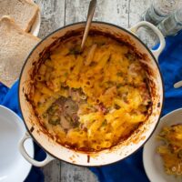 Leftover Turkey Pasta Bake in cast iron dish, served portion and slices of bread to the sides.