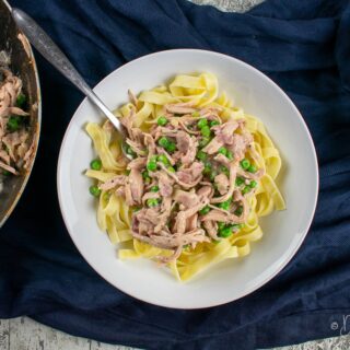served turkey and peas in cranberry sauce on top of pasta in bowl.