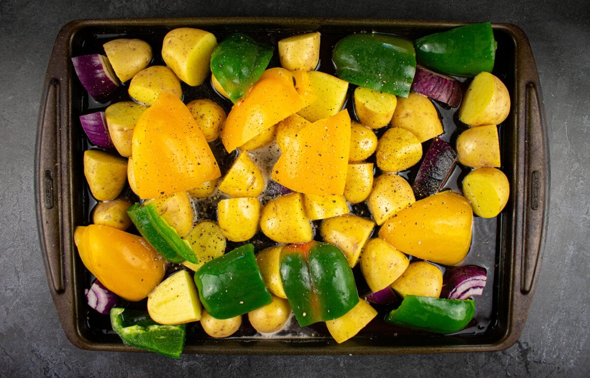 peppers and potatoes on baking tray filled with beer.