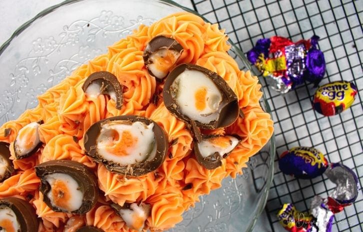 view of top of Creme Egg Loaf Cake with Creme Eggs on wire wrack to the side.