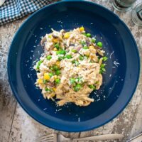 close up of served portion of risotto with leftover roast chicken on blue plate.