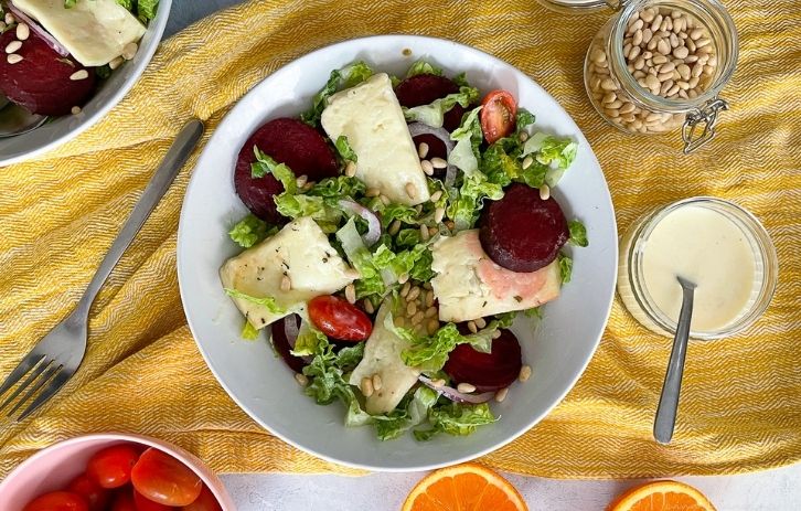 served beetroot and halloumi salad in bowl. Small jar of yoghurt and orange dressing to the side.