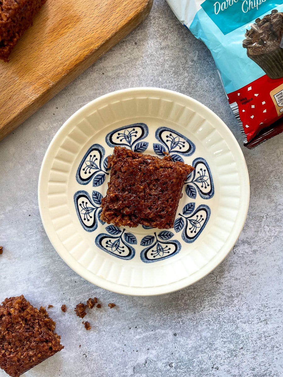 close up of square of chocolate flapjack on blue and white patterned plate.
