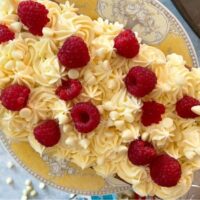 Raspberry and white chocolate loaf cake on yellow vintage cake stand.
