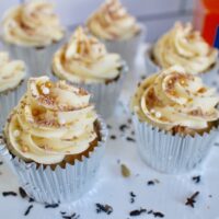 cupcakes on white stand with buttercream swirls and sprinkles.