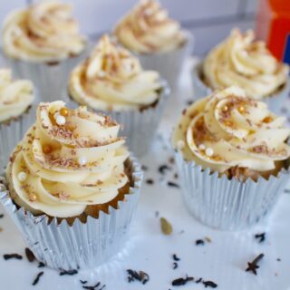 cupcakes on white stand with buttercream swirls and sprinkles.