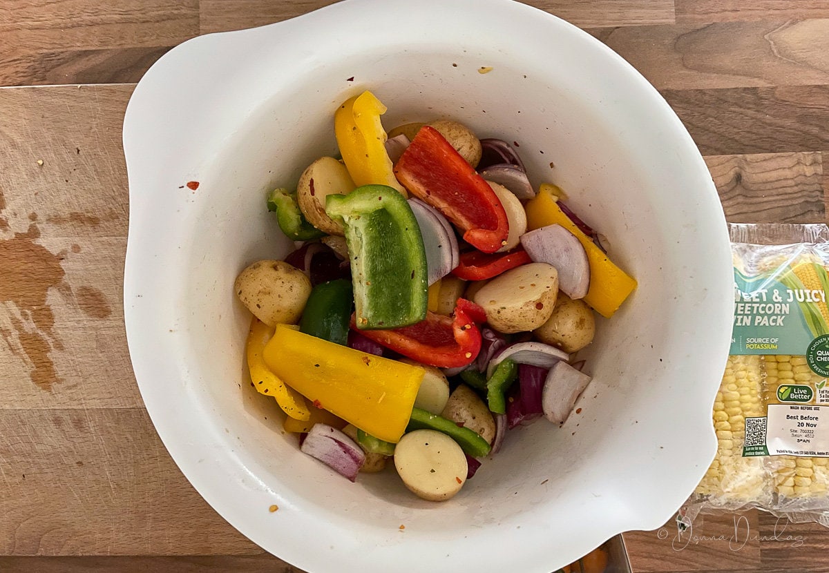 peppers, potatoes and onions in mixing bowl with peri peri seasoning.