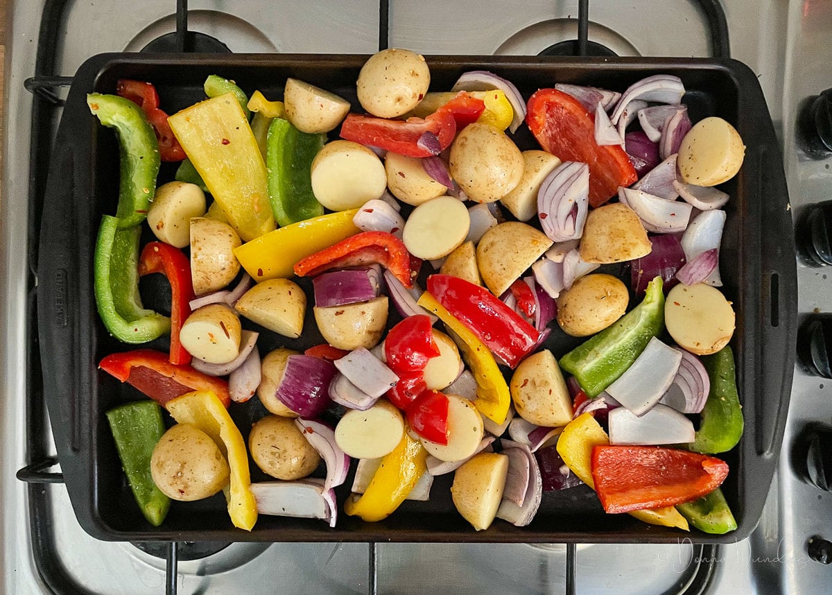 potatoes, peppers, onions spread on on baking tray.