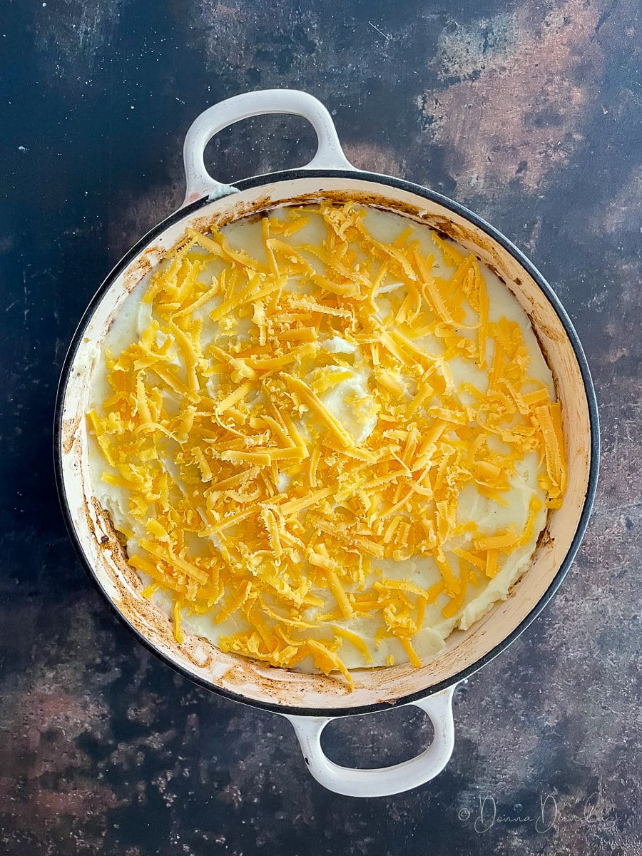 pie topped with grated cheese in cast iron dish. Unbaked.