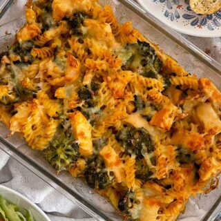 chicken and broccoli pasta bake in large glass cooking dish with serving spoon.