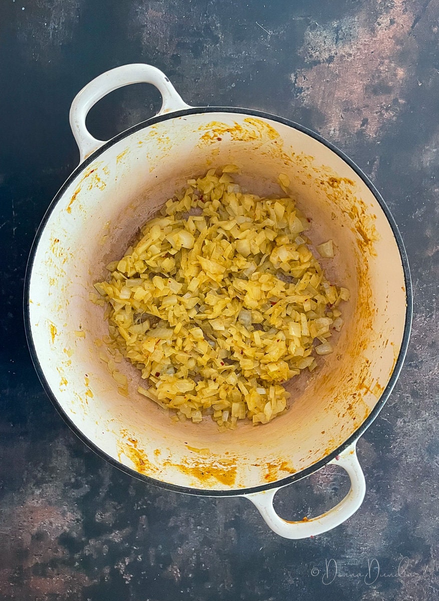 onions yellowed by curry powder in cast iron dish.