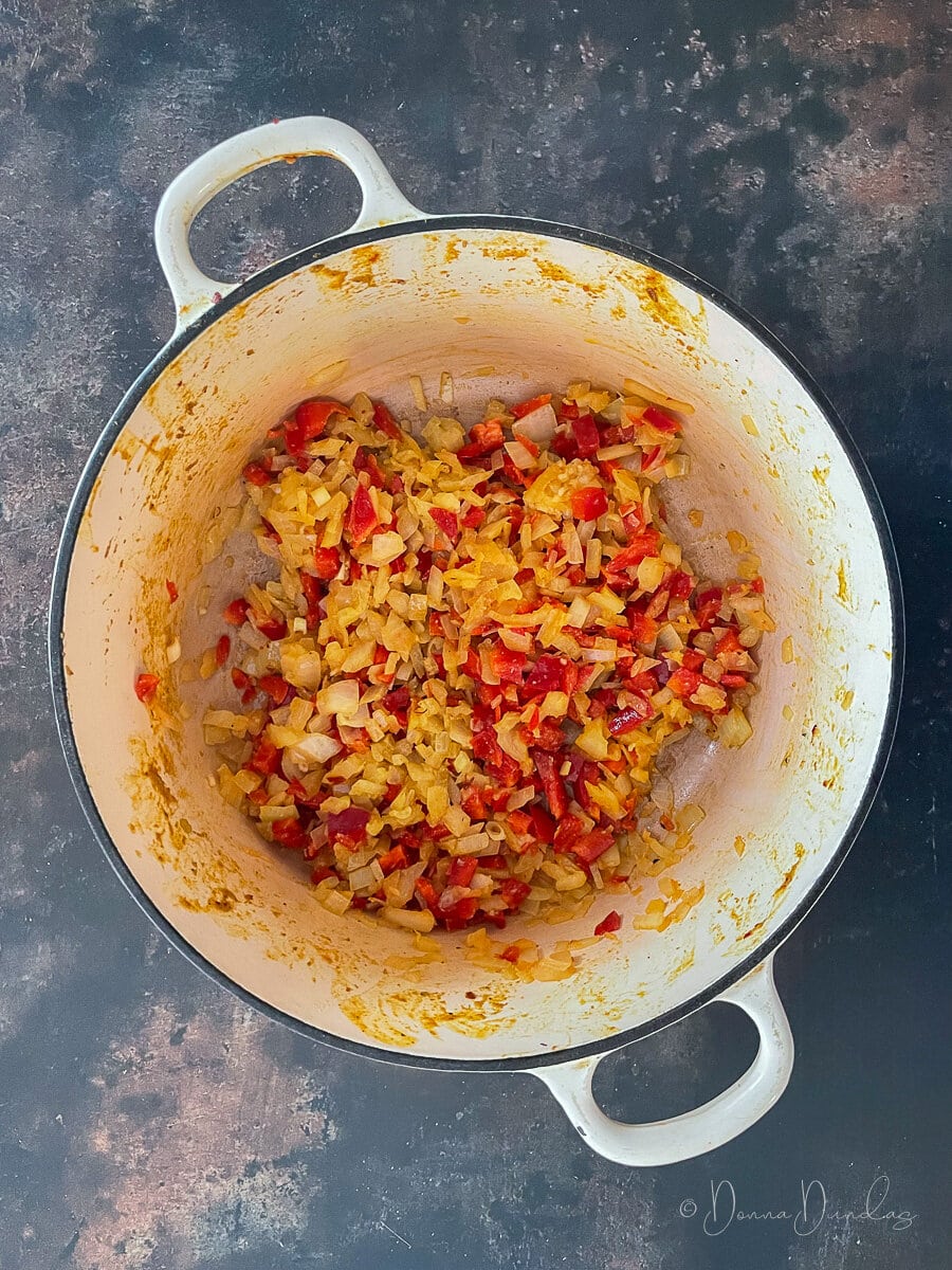 onions and red peppers with spices in cast iron dish.