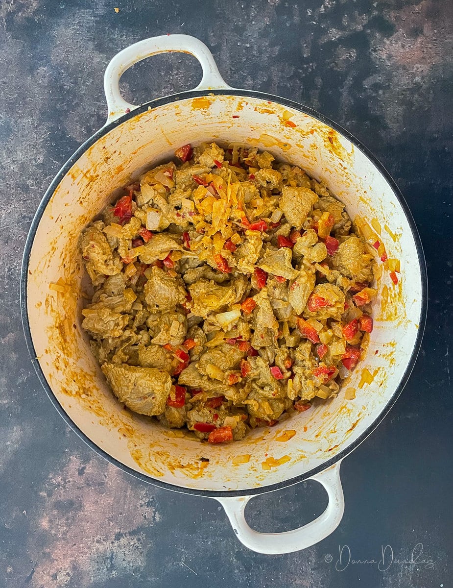 lamb marinaded in spices with onions and red pepper in cast iron dish.