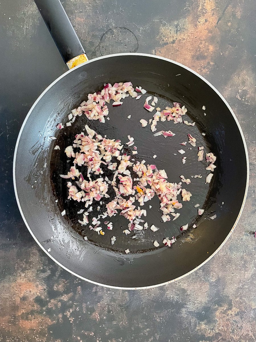 diced red onion frying in large pan.
