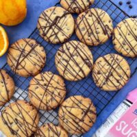 chocolate orange shortbread on a wite rack. Oranges and chocolate chips to the sides.