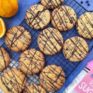 chocolate orange shortbread on a wite rack. Oranges and chocolate chips to the sides.