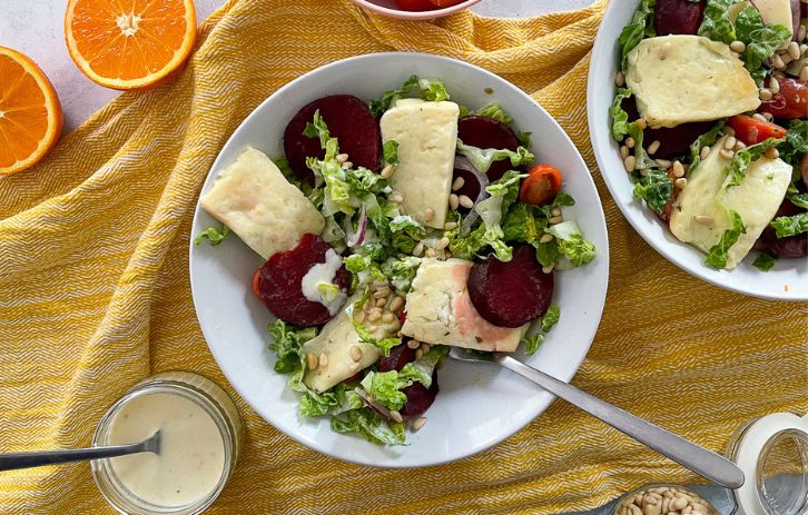 salad with beetroot and halloum in a bowl. Small ramekin with orange salad dressing to the side.