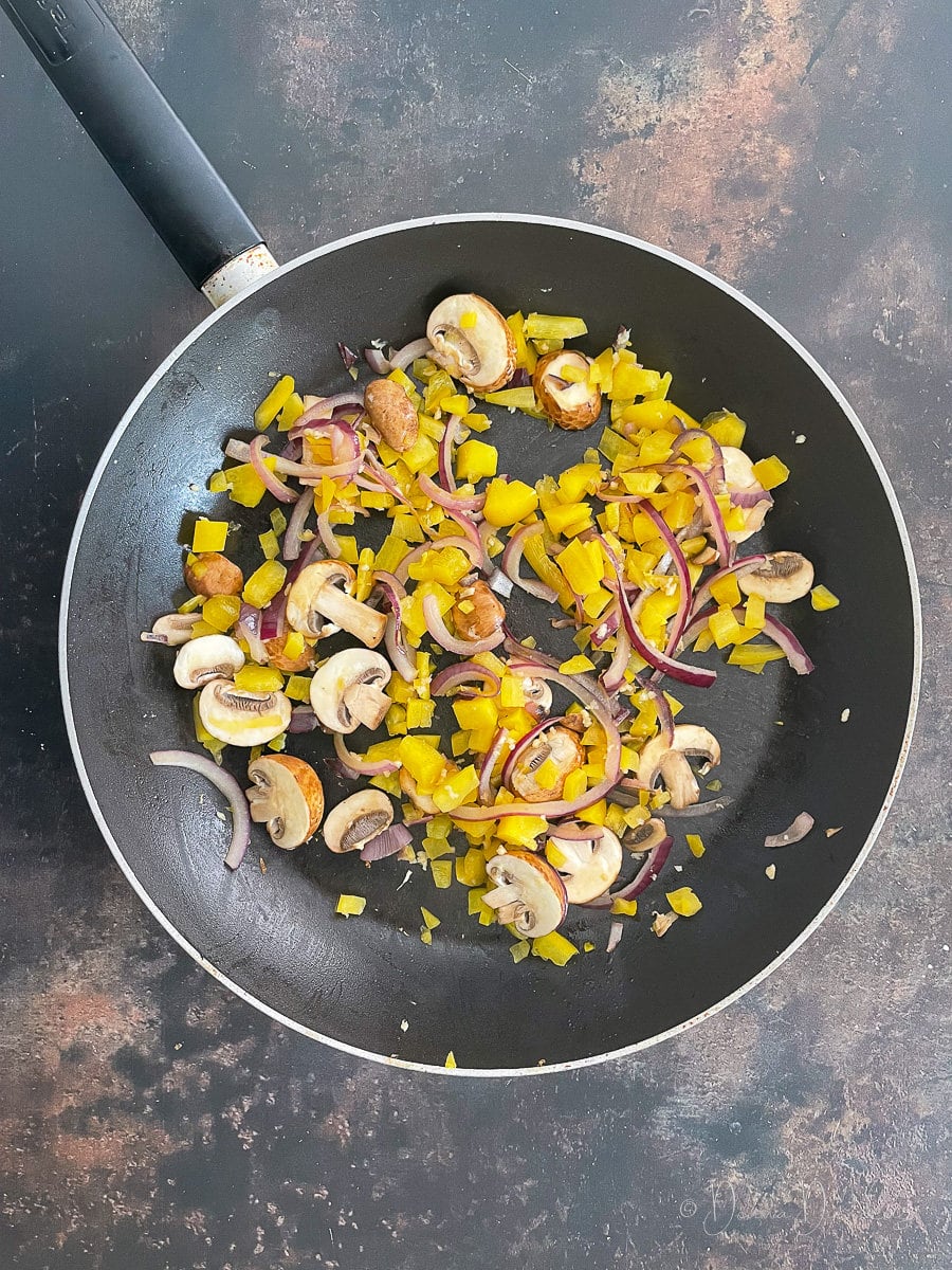 peppers, mushrooms and onions in frying pan.
