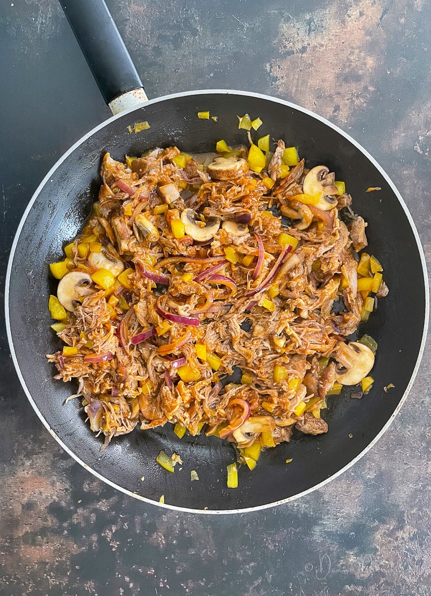 pulled pork, mushrooms, peppers in frying pan.