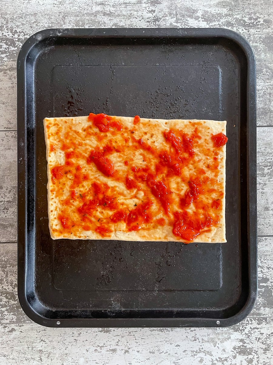 naan bread spread with tomato sauce.