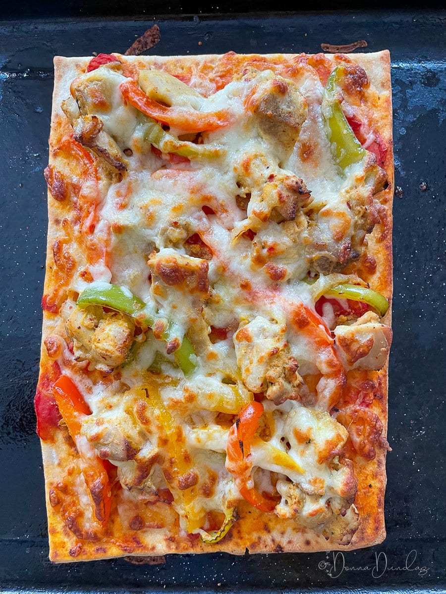 pizza with melted cheese on baking tray.
