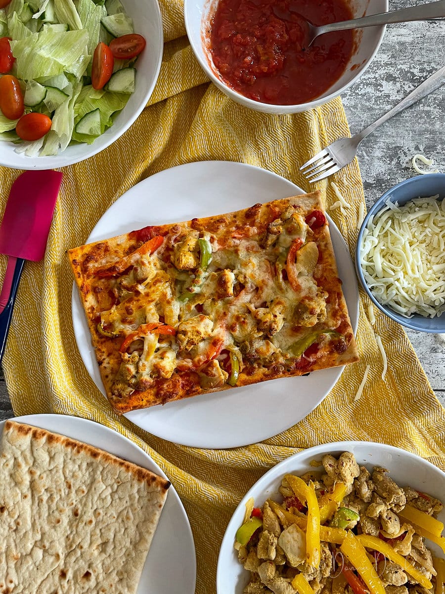 top view of chicken tikka pizza on white plate.