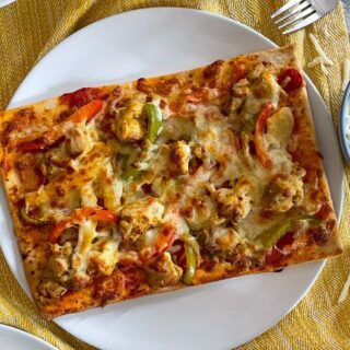 chicken tikka pizza on plate with salad.